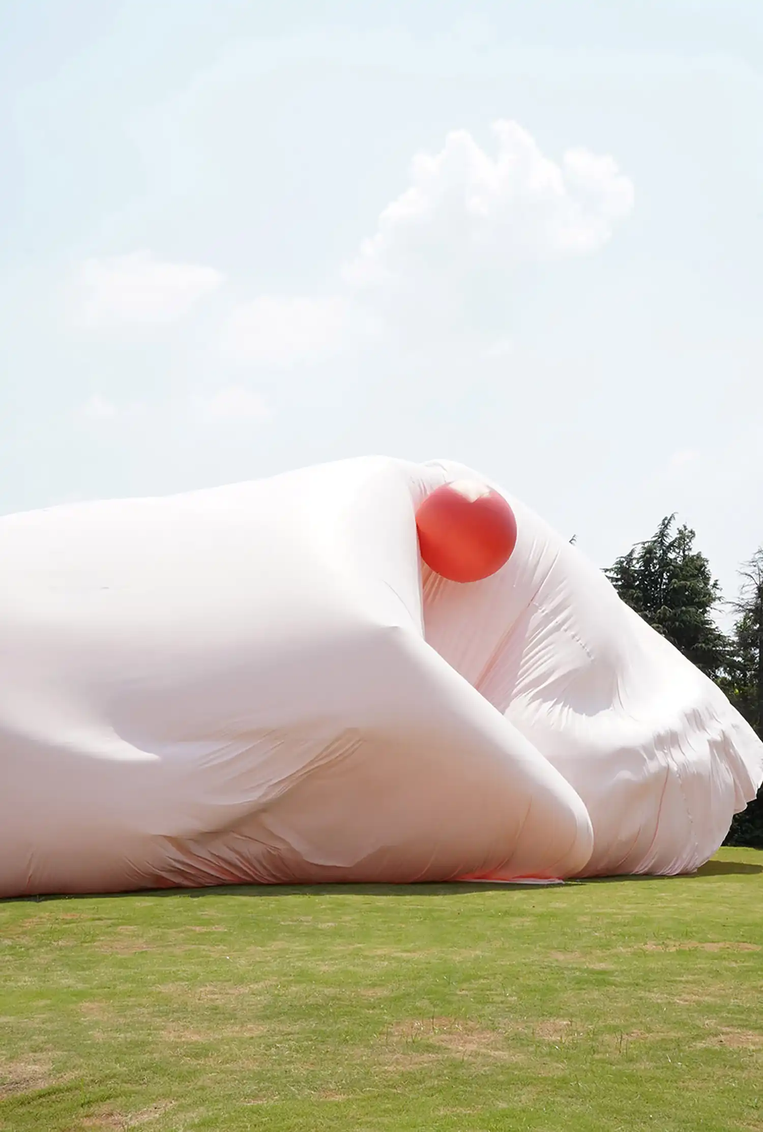 Close-up of a red balloon tucked into the folds of a voluminous pink fabric structure.