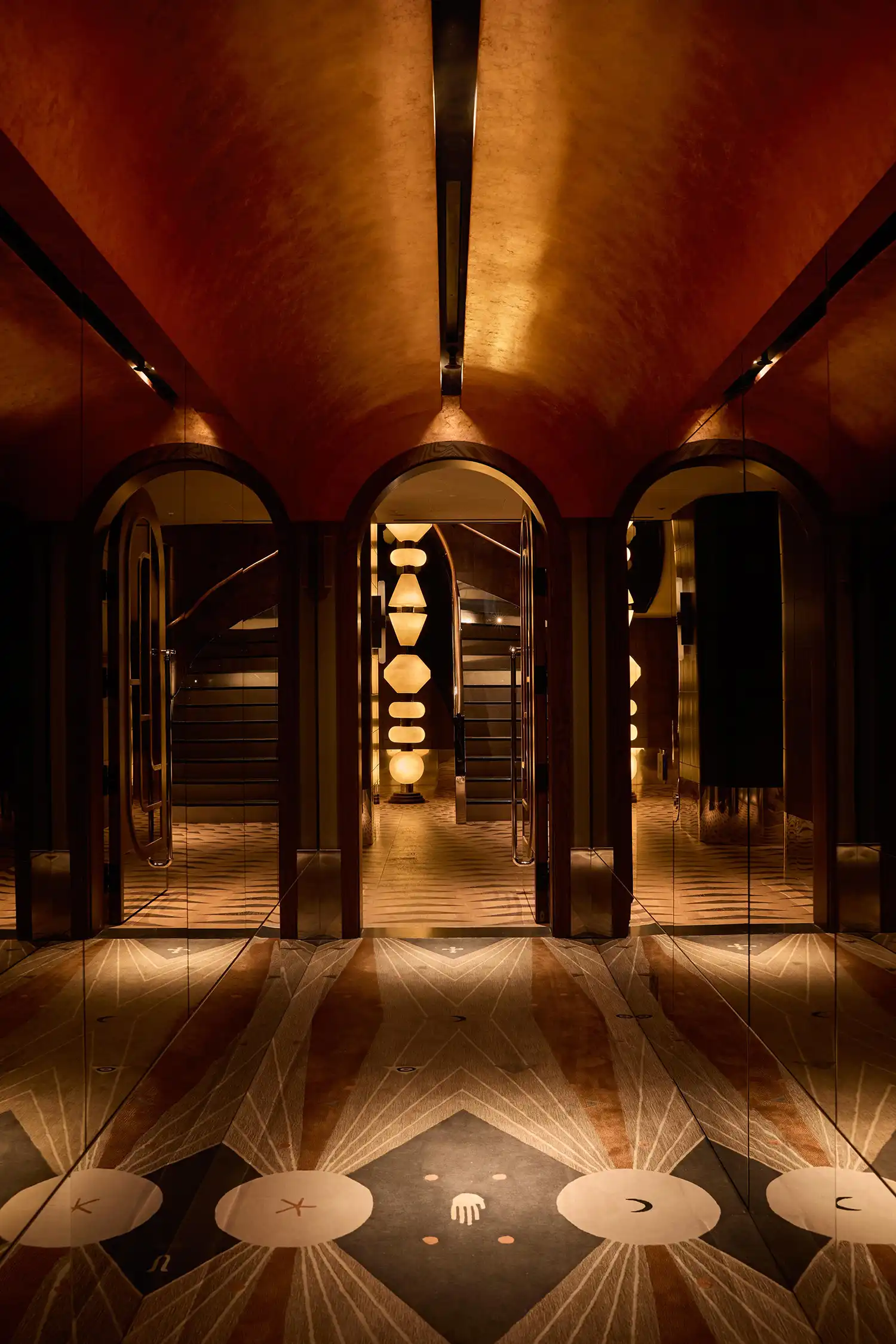 Arched mirrors and symmetrical hallway design in a luxury London hotel.