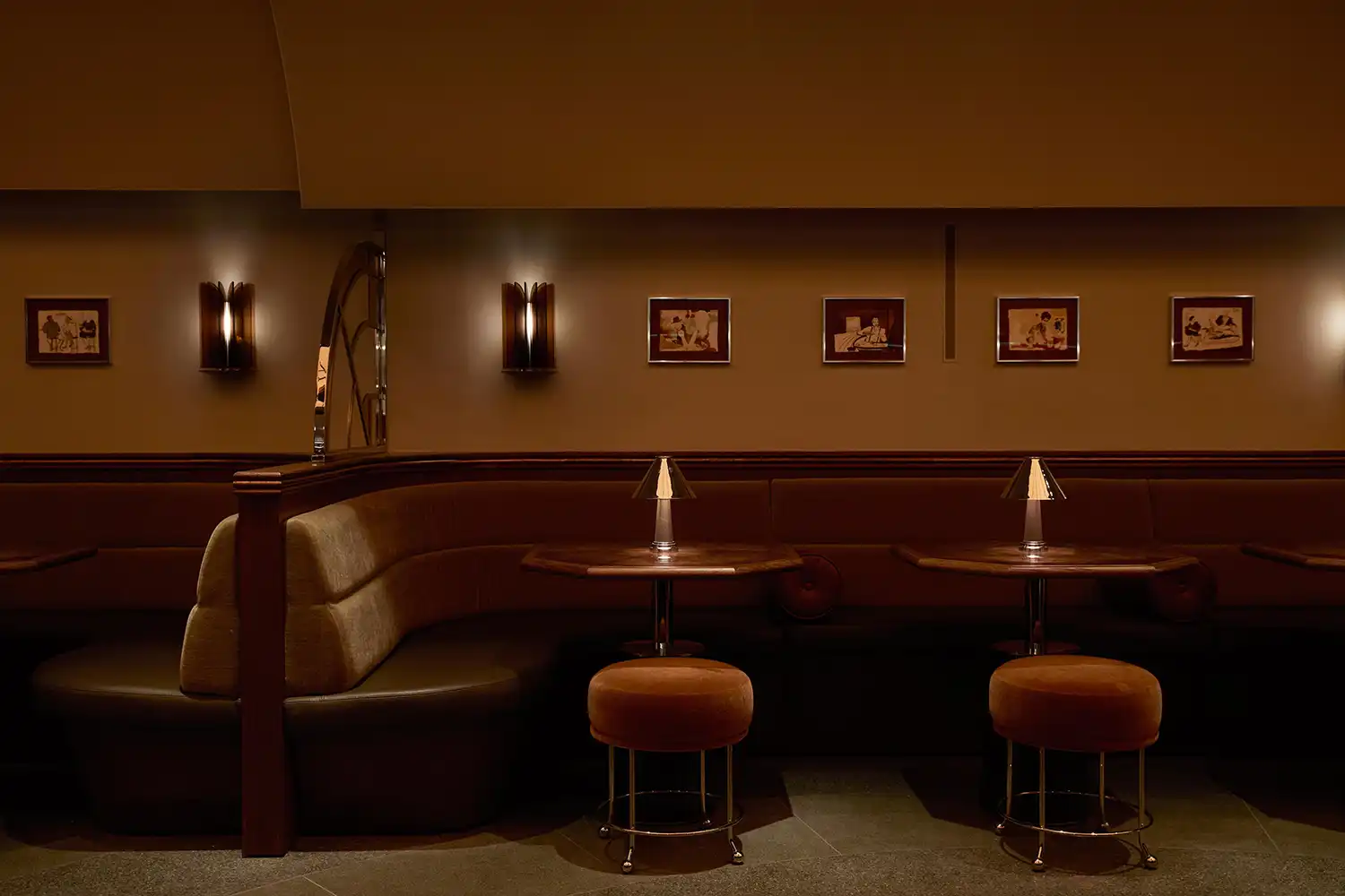 Velvet banquette seating and gallery wall with brass lighting in a hotel bar.