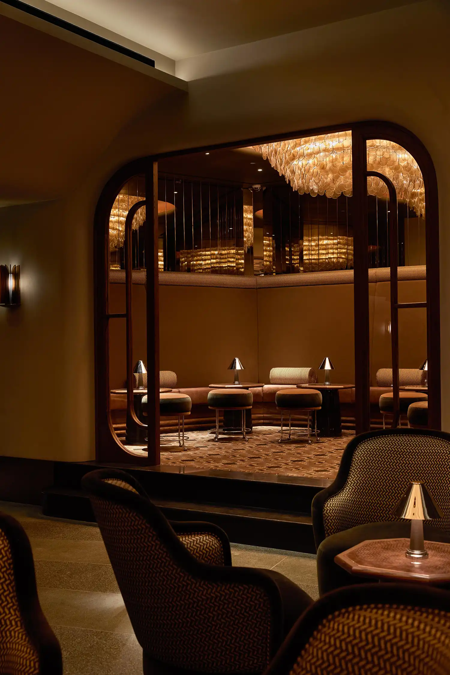 Modern club chairs and circular lounge area seen through a dark wood frame.