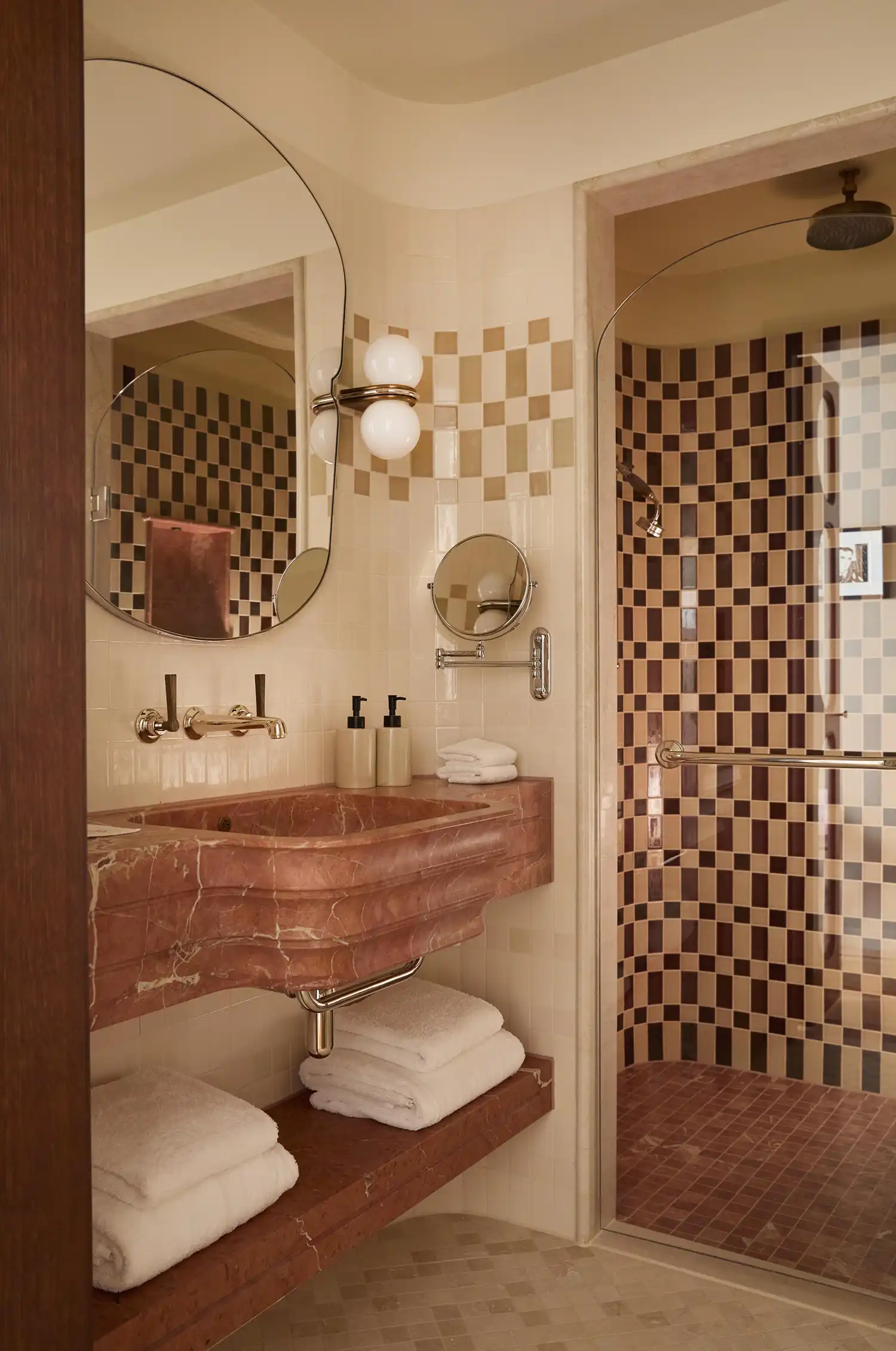 Pink marble sink and checkered tiling in a boutique hotel bathroom.