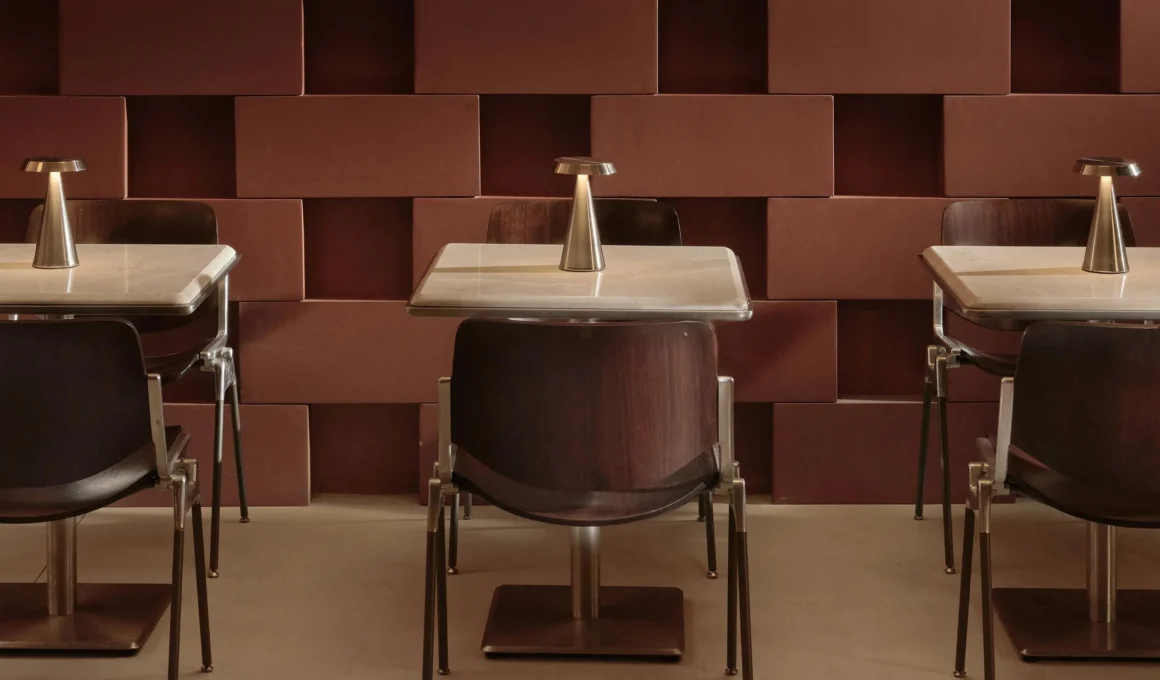 Close-up of Cassina chairs and marble tables against a textured terracotta brick wall at AINEN.