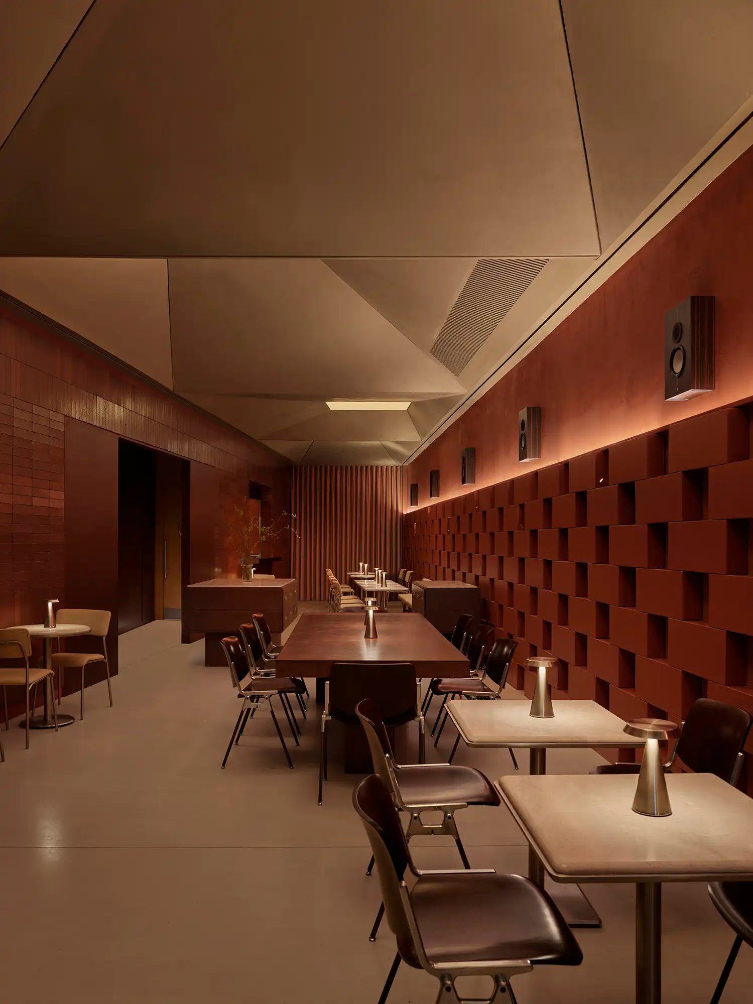 Wide view of the elongated interior of AINEN burger bar featuring a sculptural faceted ceiling.