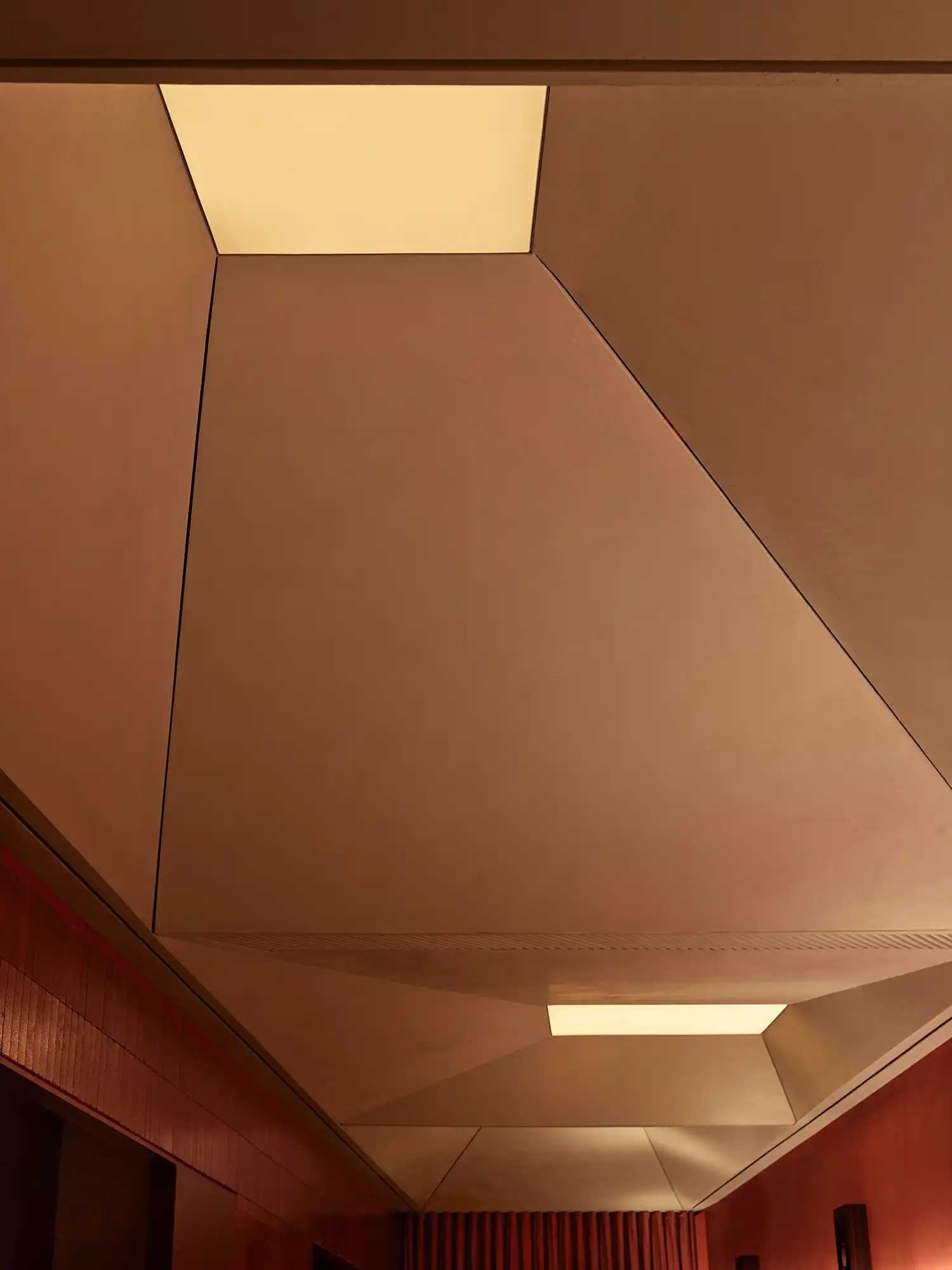 Low-angle shot of the sculptural faceted ceiling panels and integrated skylights.