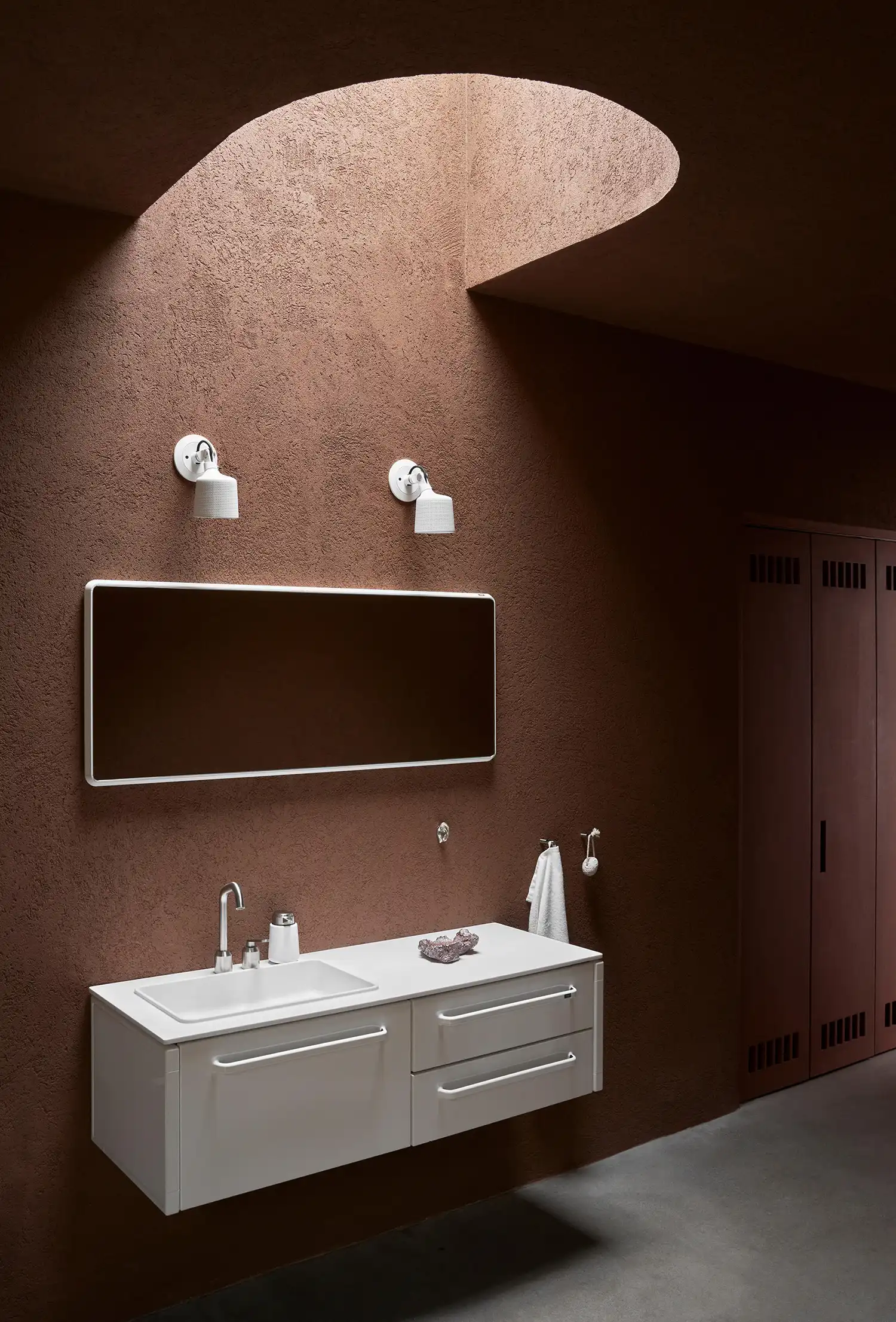 Ochre-walled bathroom with a white floating vanity and a circular skylight illuminating the space.