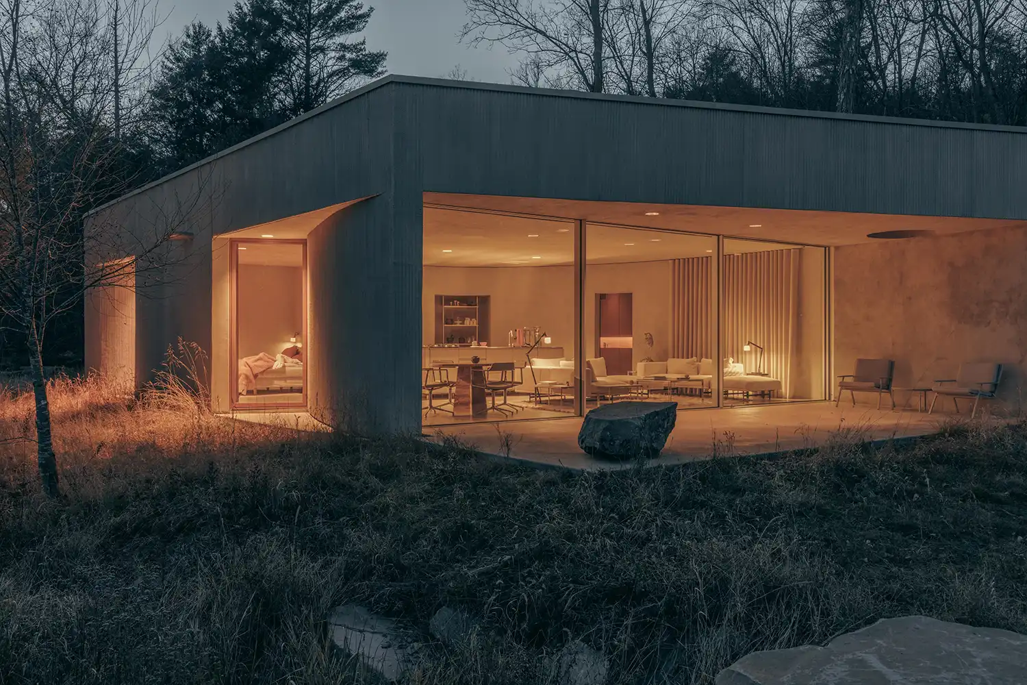 Evening shot of the Vipp Pavilion illuminated from within, showcasing the interior through large glass panes.