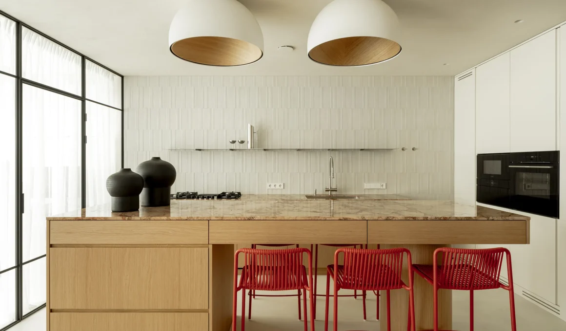 Minimalist kitchen island with Italian Breccia Pernice marble top and red Pedrali stools.