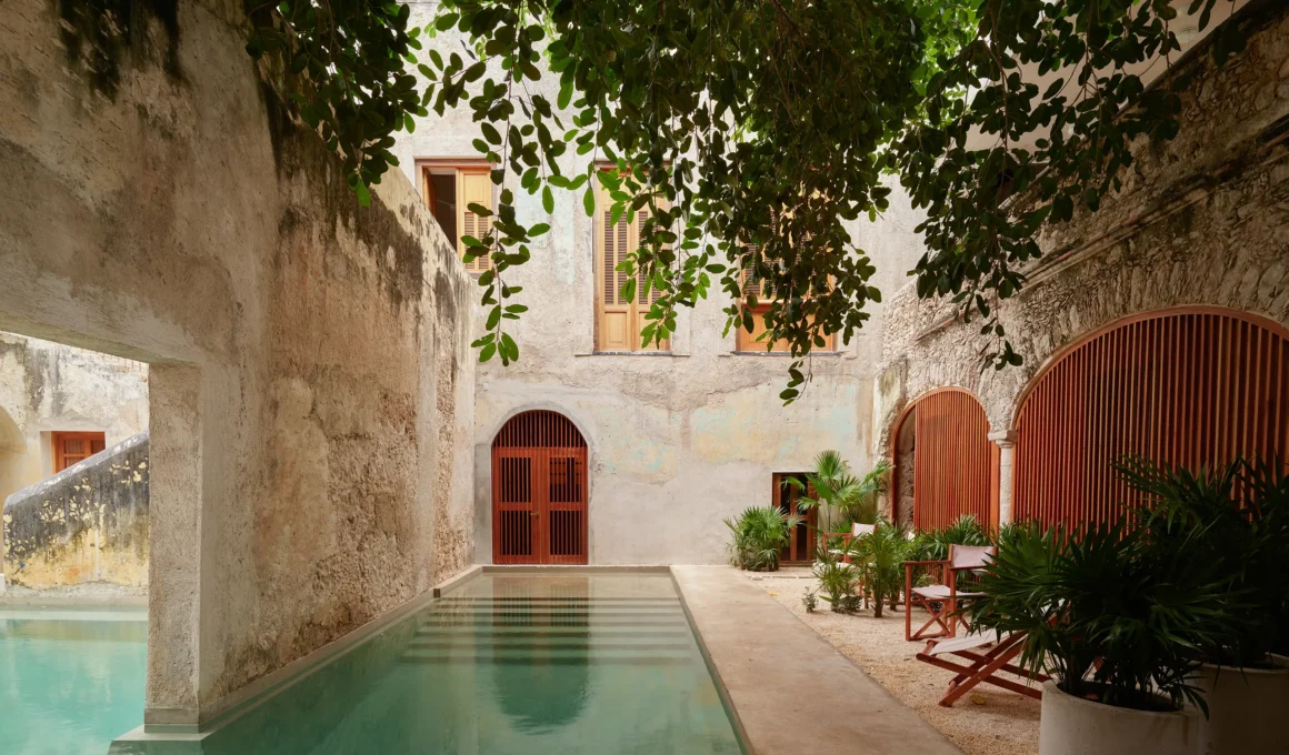 Private courtyard at Hotel Sevilla in Merida with a concrete pool and lush greenery.