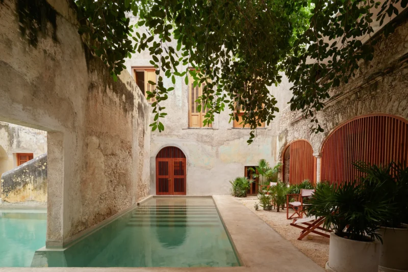 Private courtyard at Hotel Sevilla in Merida with a concrete pool and lush greenery.