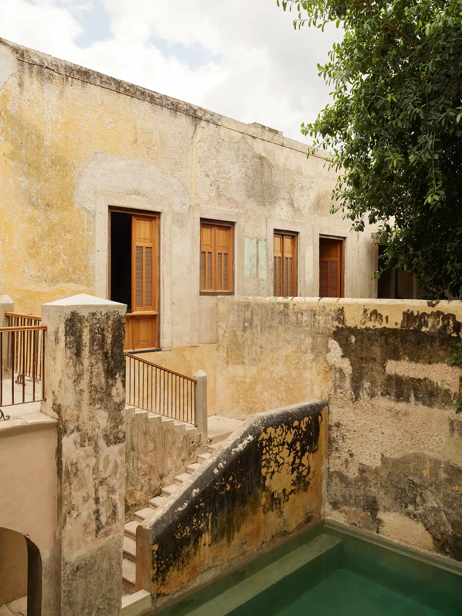 Weathered stone walls and modern stairs overlooking the pool at Hotel Sevilla.
