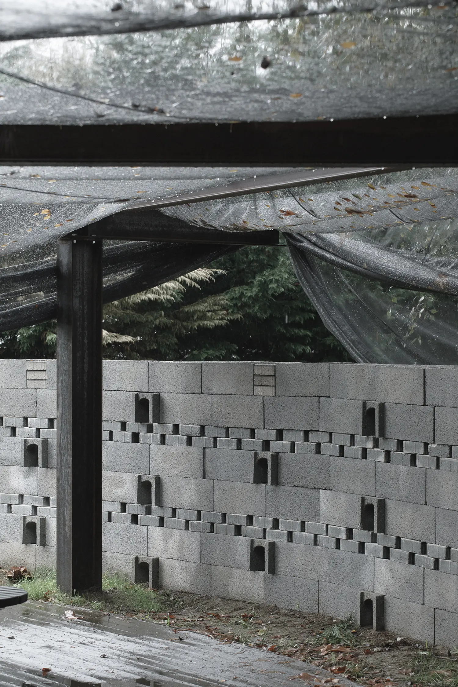 A straight-on, close-up interior shot focusing on the texture and void pattern of the gray concrete block wall in the Rotação pavilion by Atelier Tiago Antero.