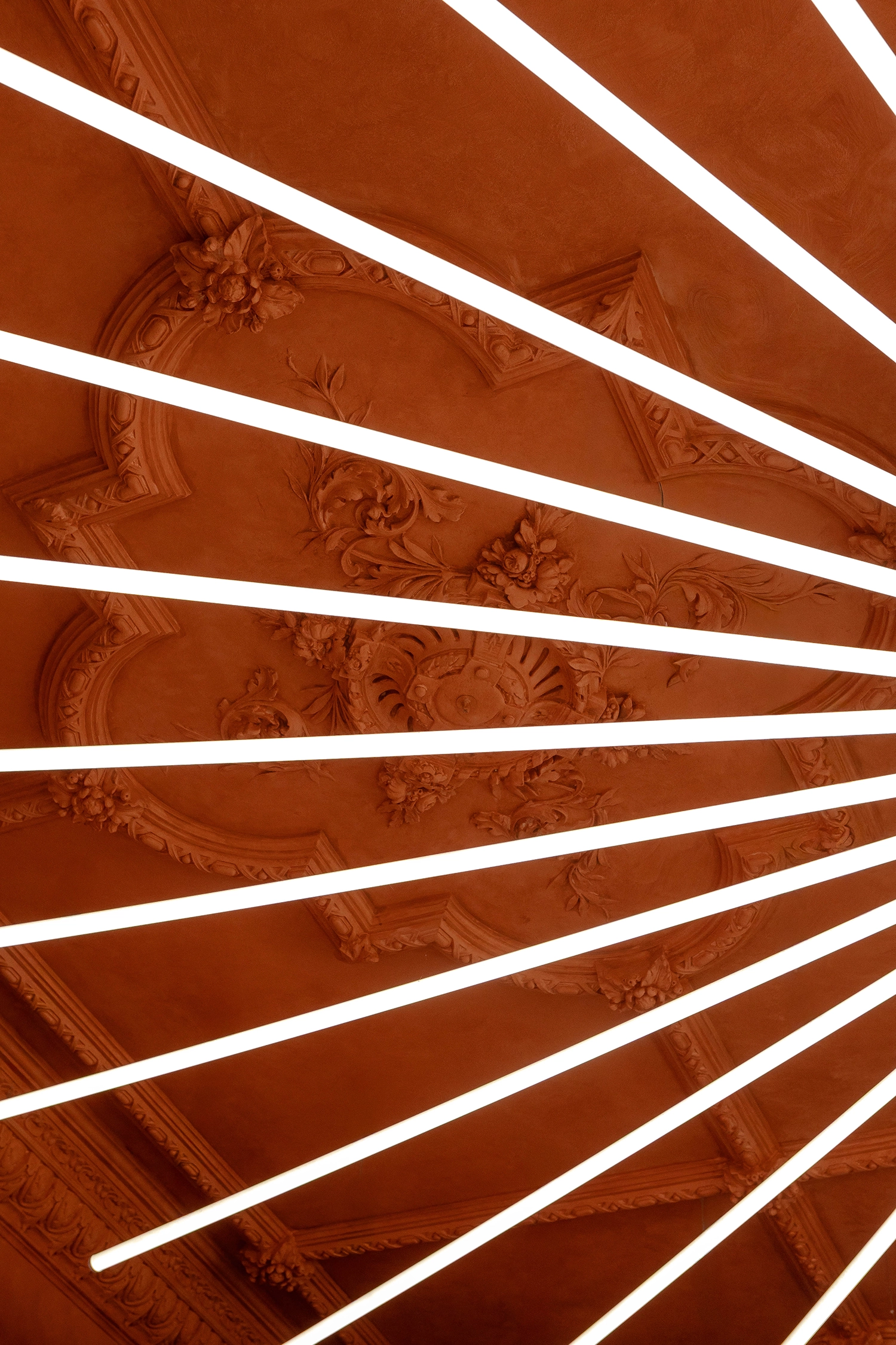 Close-up detail of intricate 19th-century ceiling cornices overlaid with modern white linear light tubes.