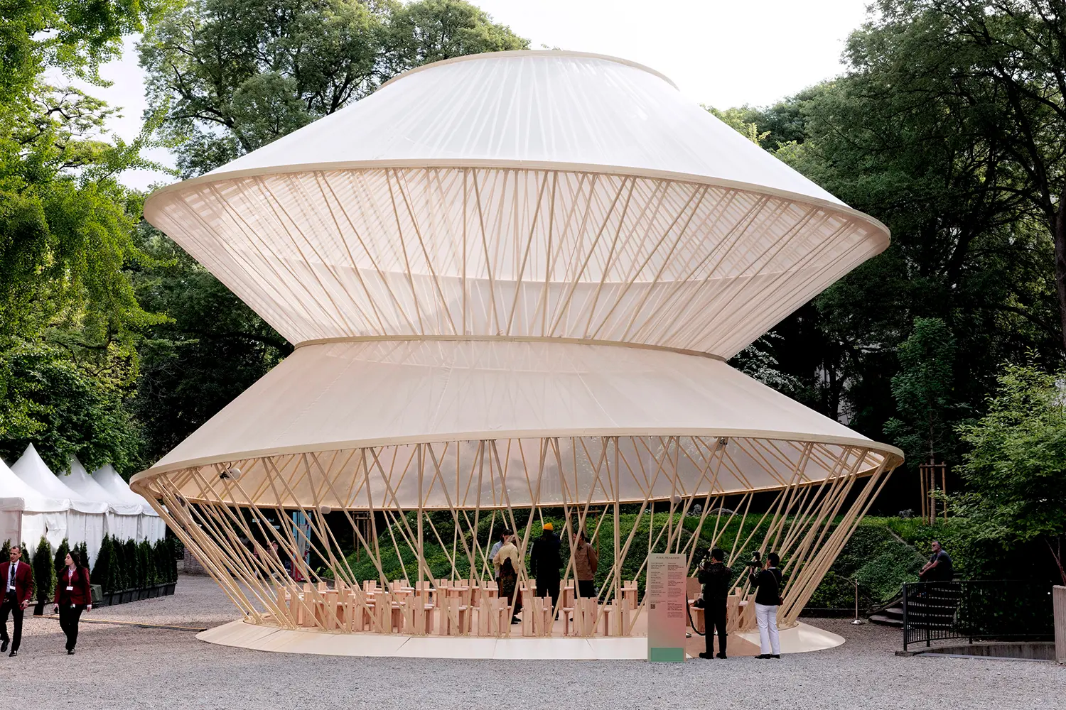 Bioclimatic pavilion in wood and white fabric inspired by apricot blossoms.