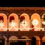 Illuminated LED knots by BIG and Artemide glowing against the Renaissance arches of the University of Milan at night.