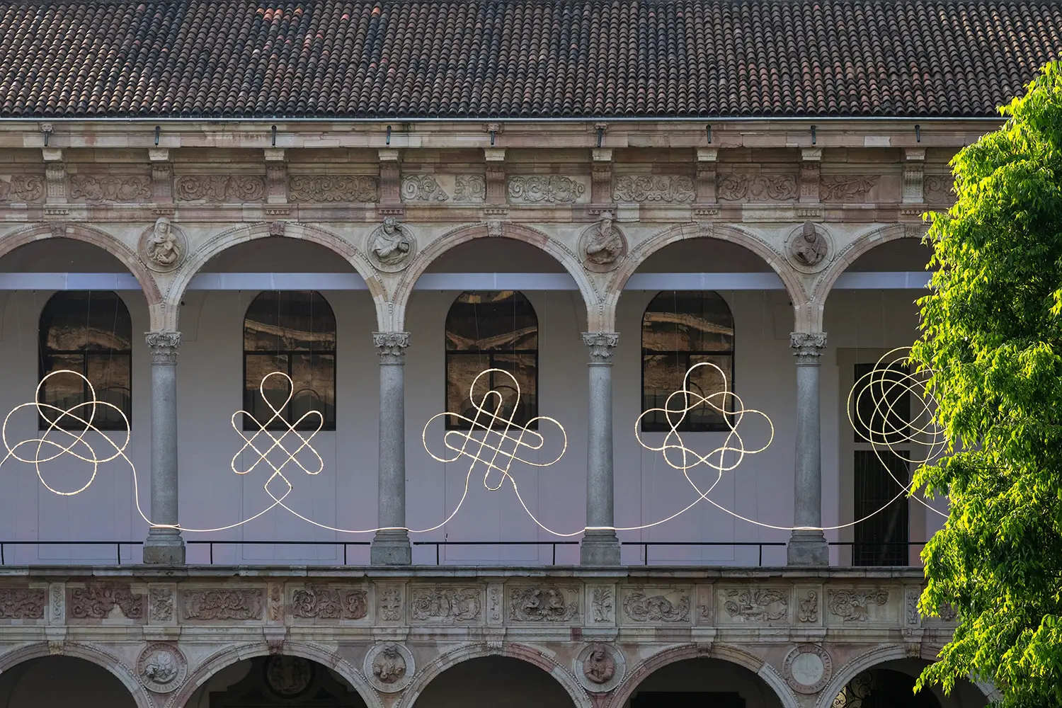 A daytime view of the 280-meter Light Knot Progression installation stretching across the loggia of the Cortile d’Onore.
