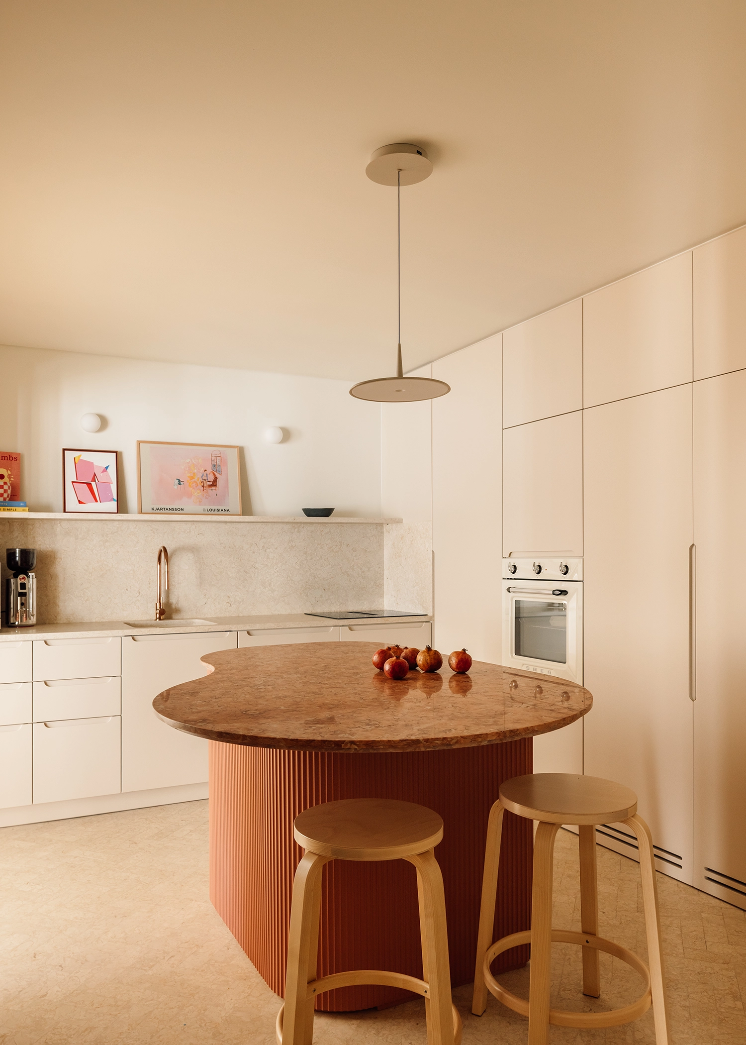 Modern kitchen with cream minimalist cabinets and a curved terracotta island with an organic-shaped marble top.