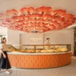 Interior view of Pierre Hermé Singapore featuring a circular counter and a large red petal-like ceiling installation.