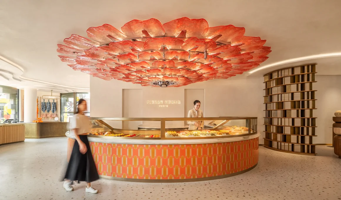 Interior view of Pierre Hermé Singapore featuring a circular counter and a large red petal-like ceiling installation.