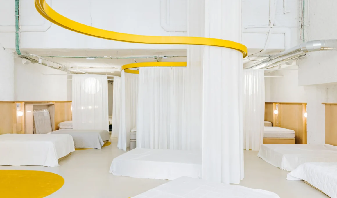 Interior view of Colchón Exprés Madrid featuring yellow curved ceiling tracks and white privacy curtains.