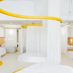 Interior view of Colchón Exprés Madrid featuring yellow curved ceiling tracks and white privacy curtains.