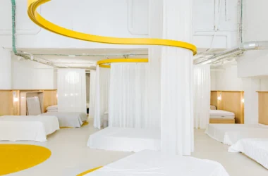 Interior view of Colchón Exprés Madrid featuring yellow curved ceiling tracks and white privacy curtains.