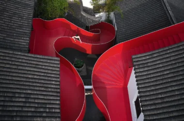 Aerial view of a winding red steel staircase between traditional Chinese grey tiled roofs in Nanjing.
