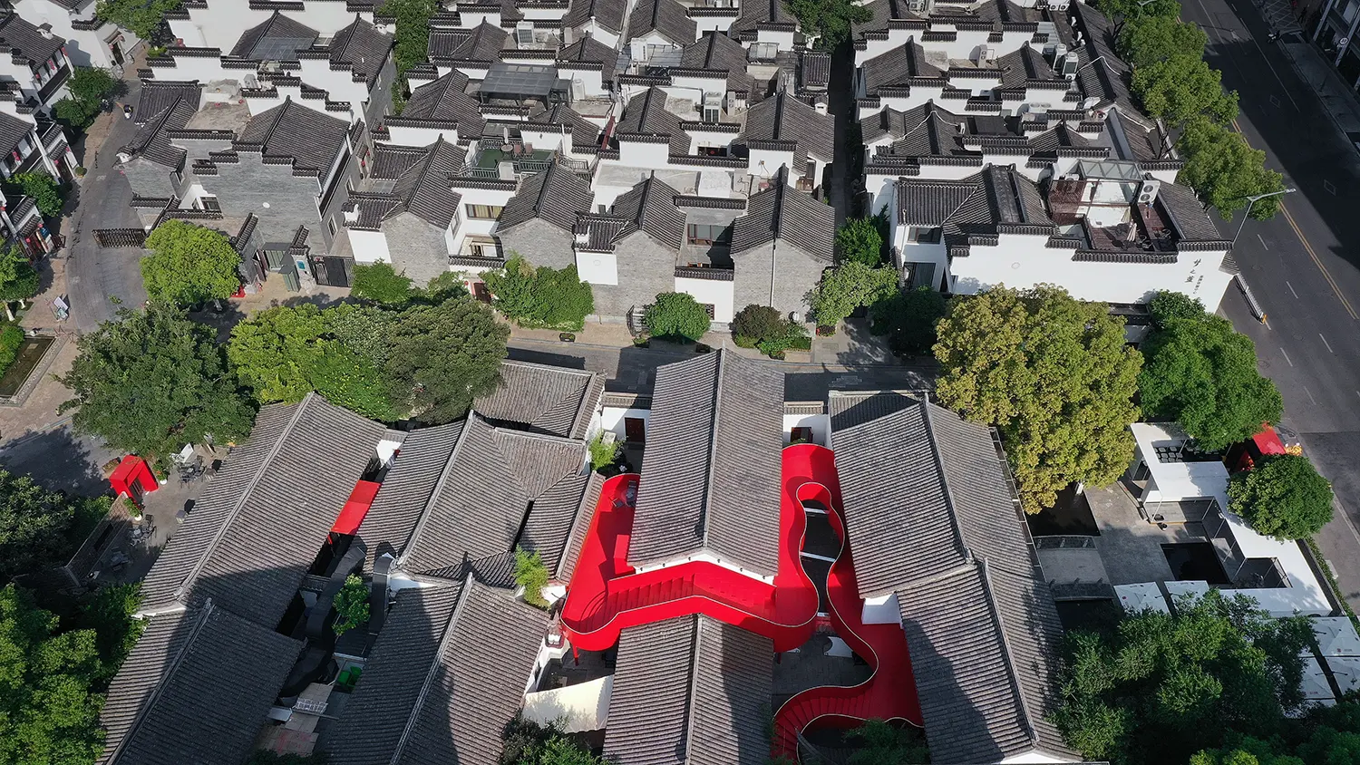 Wide drone shot of a historic district in Nanjing featuring a bright red architectural intervention.