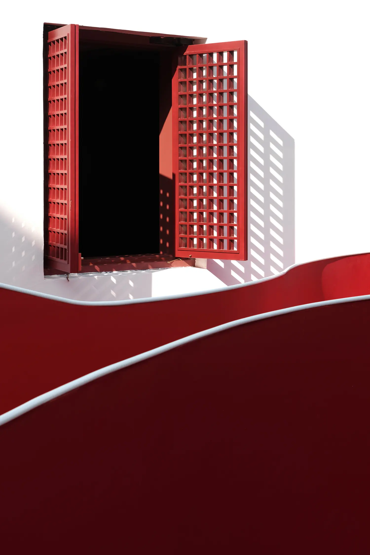 Close-up of a red latticed window and the curve of a red steel walkway in Nanjing.