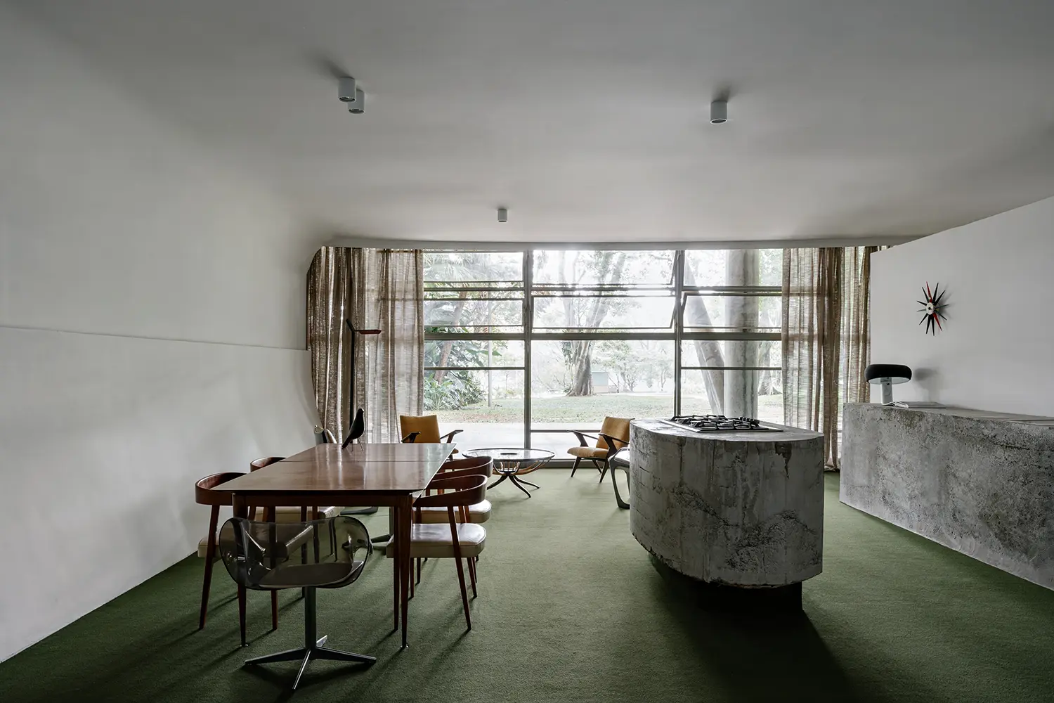 Open-plan interior architecture with green carpet and Niemeyer-designed window frames.