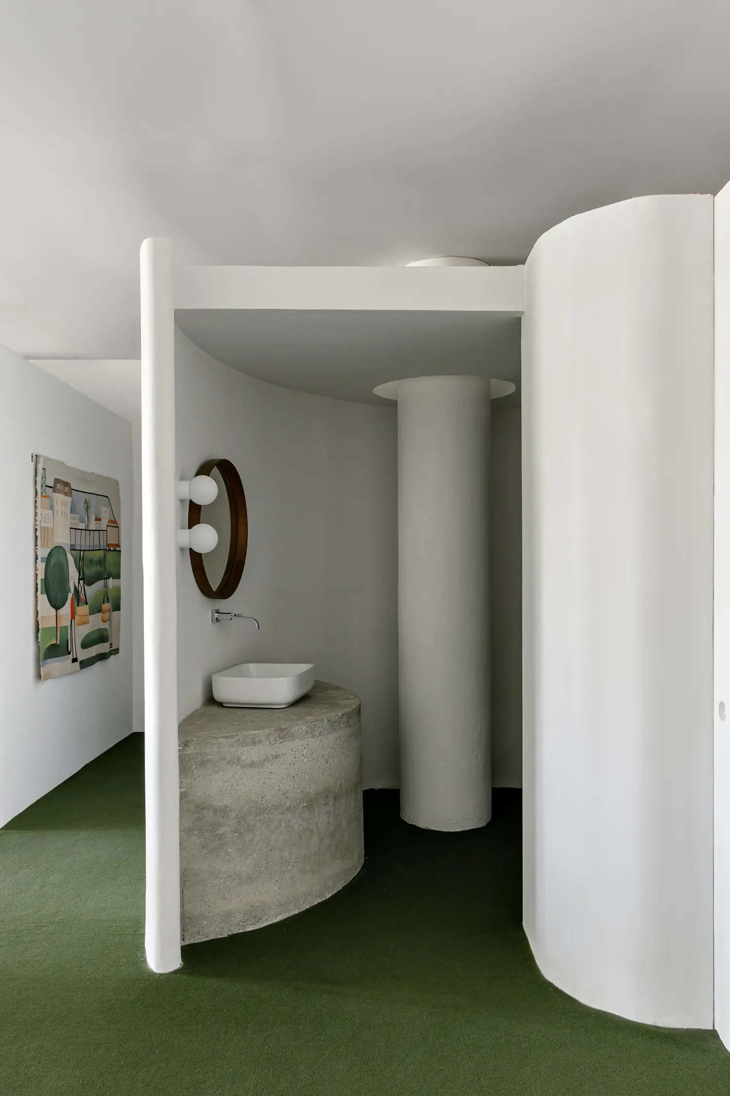 Concrete bathroom vanity with round mirror and integrated white pilotis column.