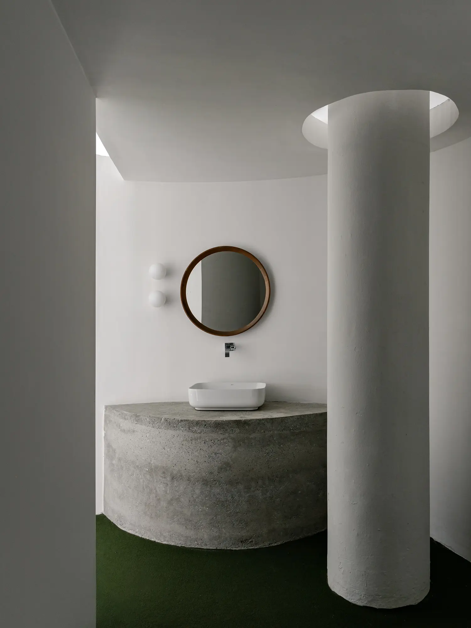 Architectural detail of a concrete washbasin and white structural column under soft light.