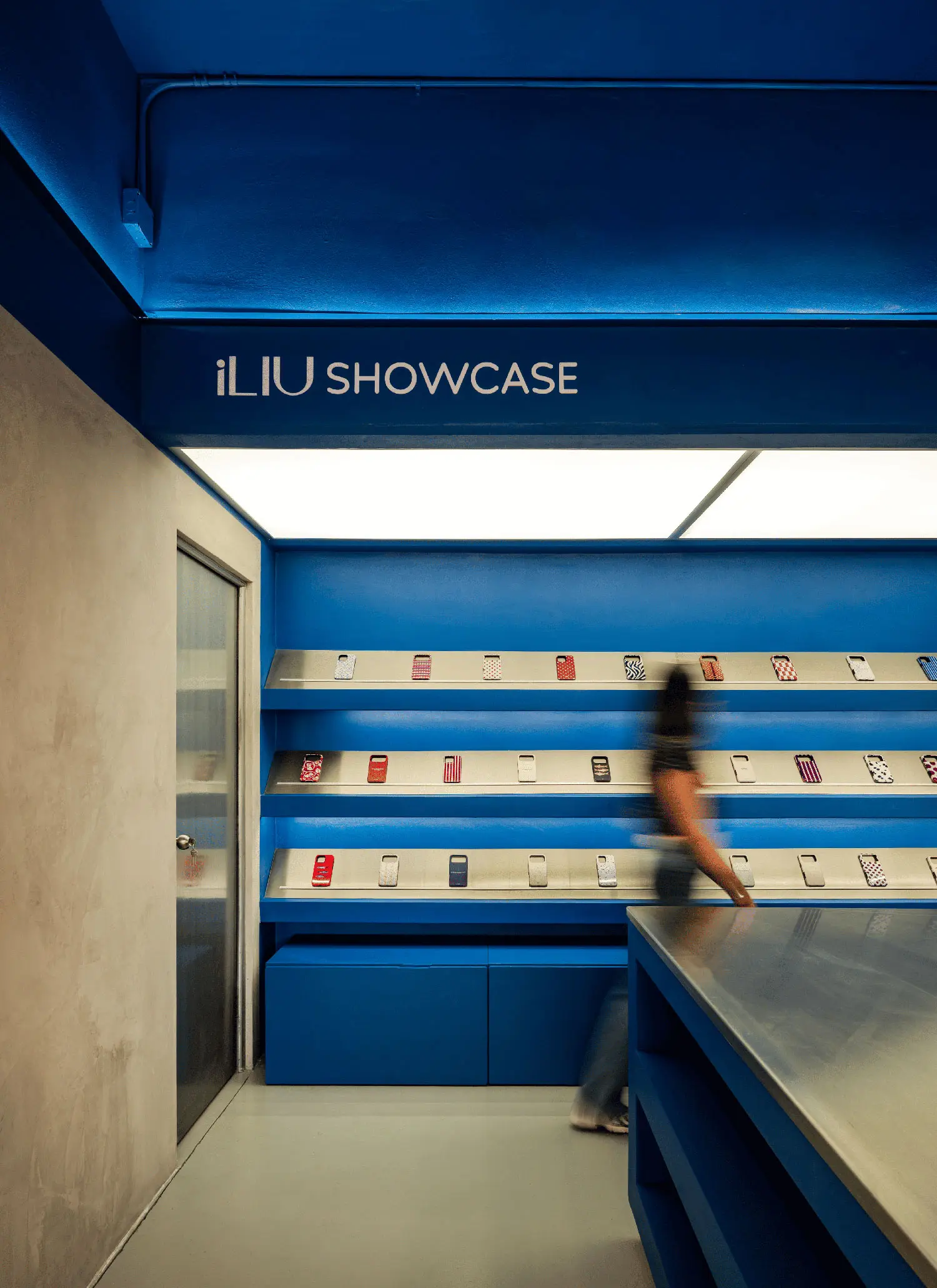 Close-up of iLIU Showcase area with backlit ceiling and tiered metal product displays.