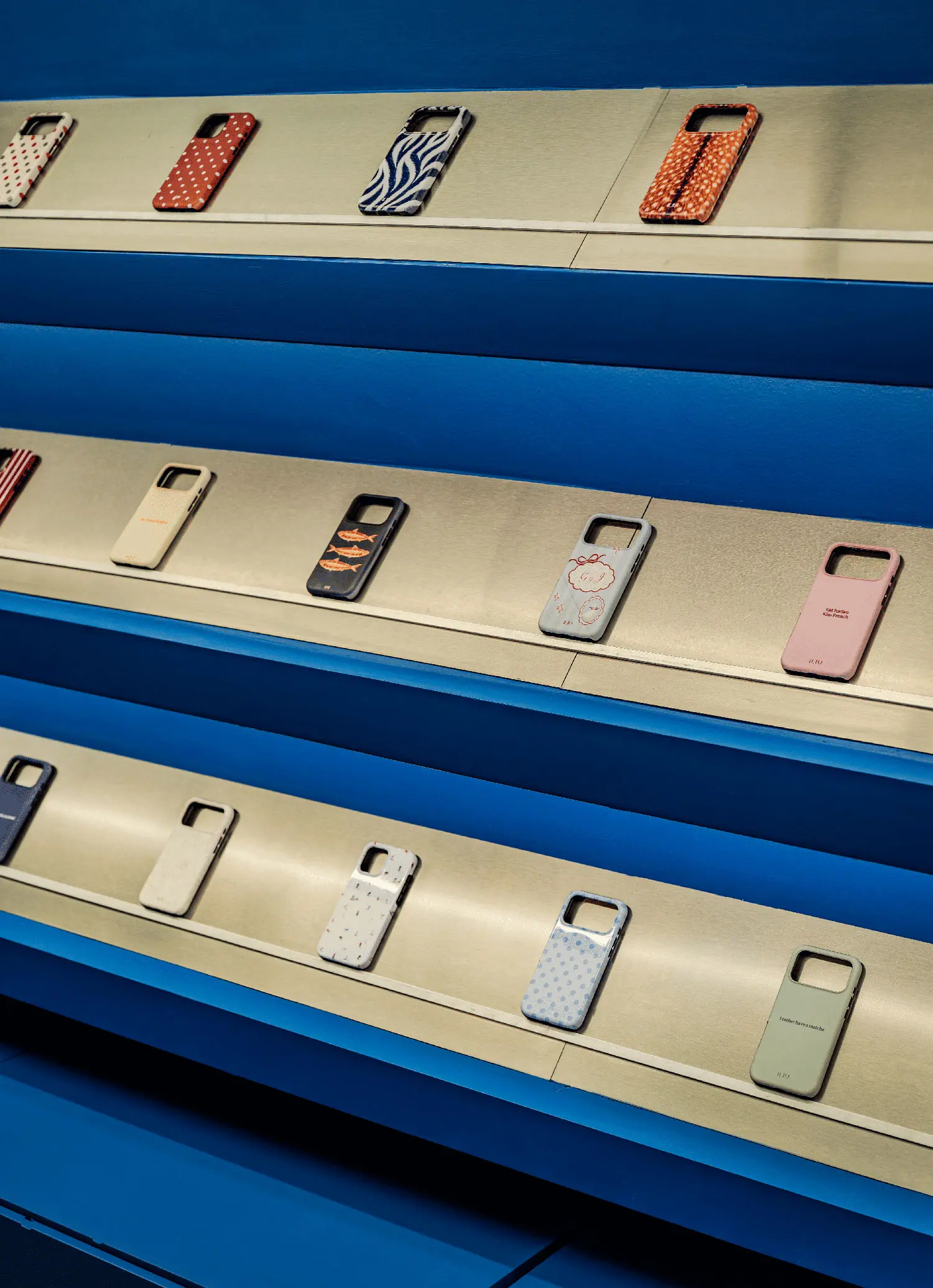 Detailed view of phone cases arranged on angled galvanized steel shelves at iLIU Experience.
