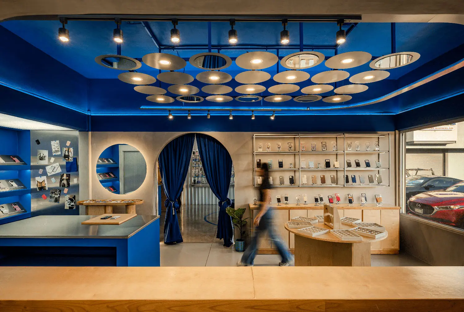 Interior view toward the rear of the store with blue velvet curtains and custom metal ceiling lighting.