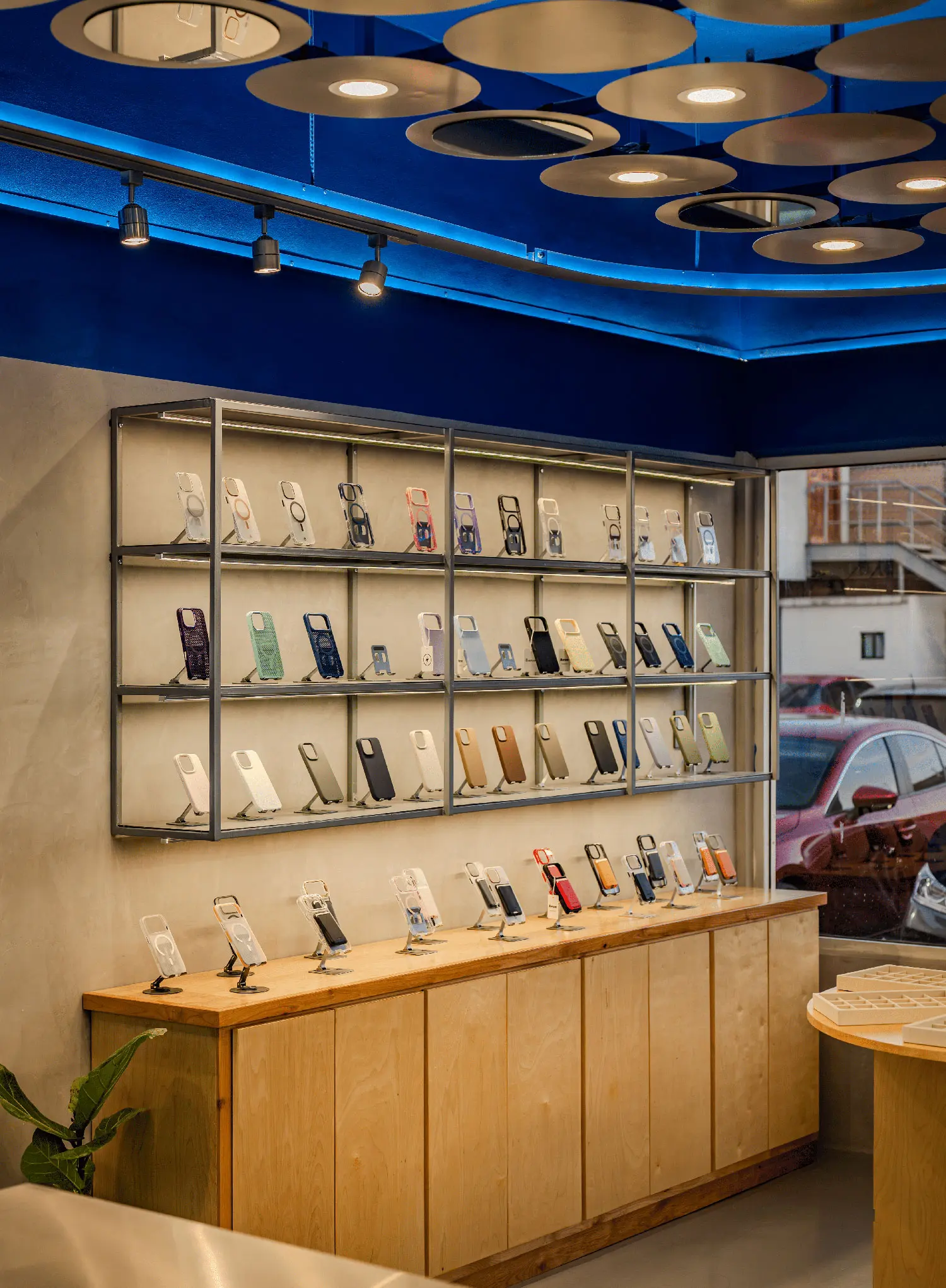 Minimalist metal shelving unit against a concrete-finish wall with wooden cabinetry below.