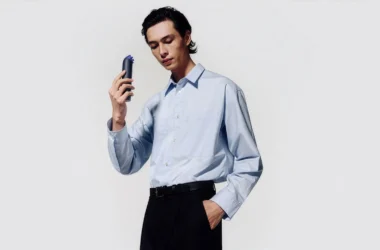 A person holding a navy blue Dyson HushJet Mini Cool portable fan against a white background.