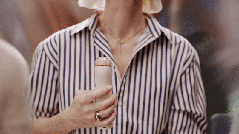 Close-up of a person holding the Stone and Blush Dyson HushJet Mini Cool fan.