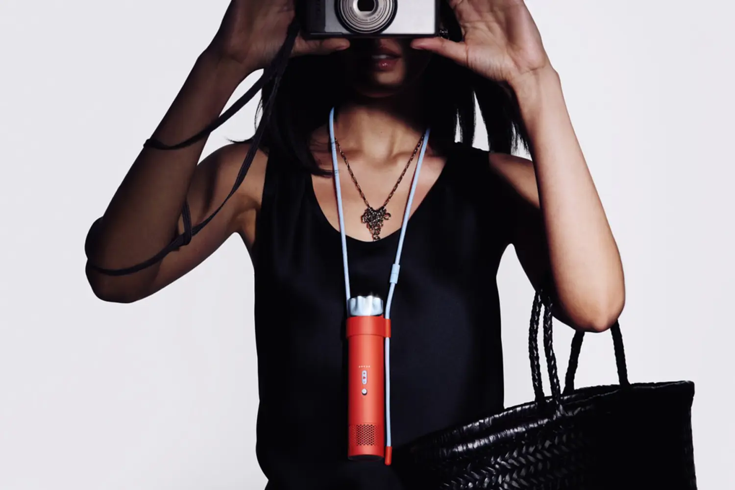 A person wearing the Dyson HushJet Mini Cool around their neck using a light blue lanyard.