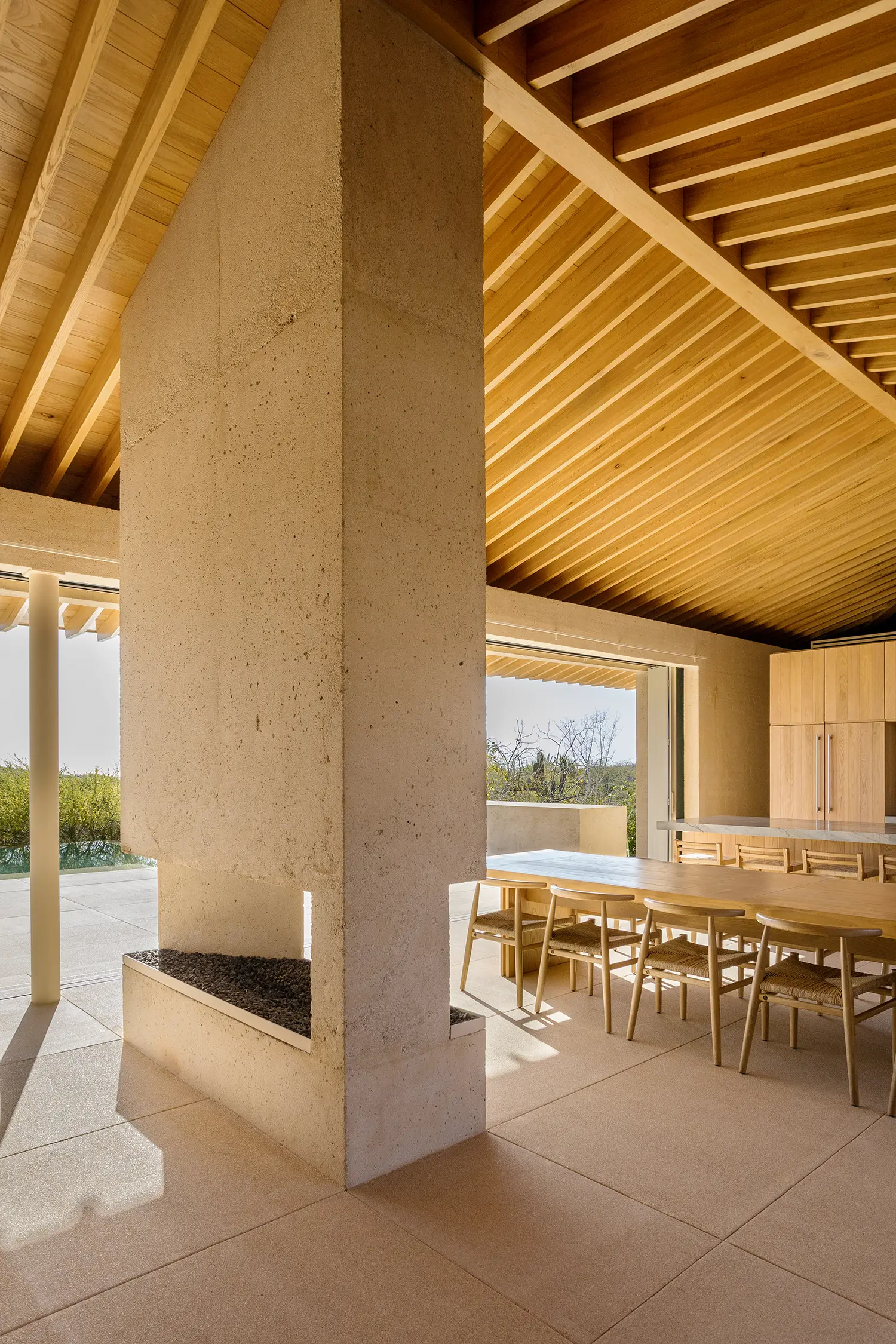 Vertical shot of a tall concrete fireplace column reaching toward a pitched wooden beam ceiling.