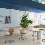 Curving wooden continuous table with integrated plants and Marlon Brando portrait in Madrid office.
