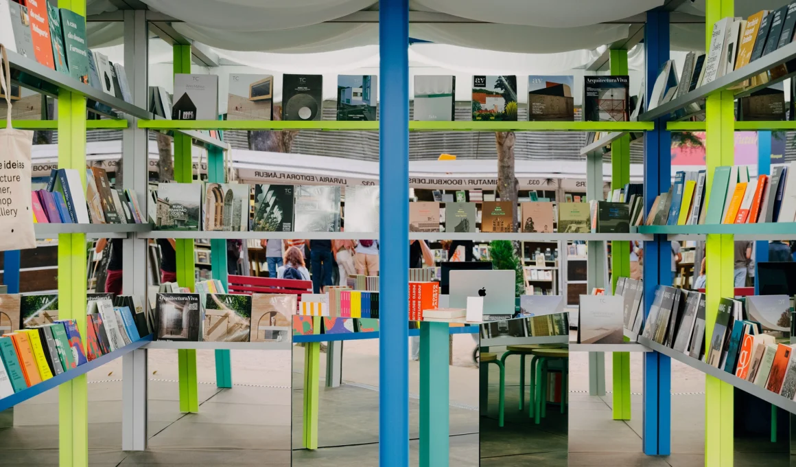 Interior view of Circo de Ideias stand showing a blue central column and mirrored walls reflecting colorful bookshelves.