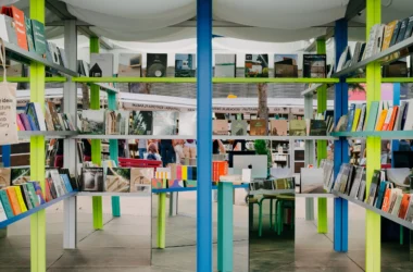 Interior view of Circo de Ideias stand showing a blue central column and mirrored walls reflecting colorful bookshelves.