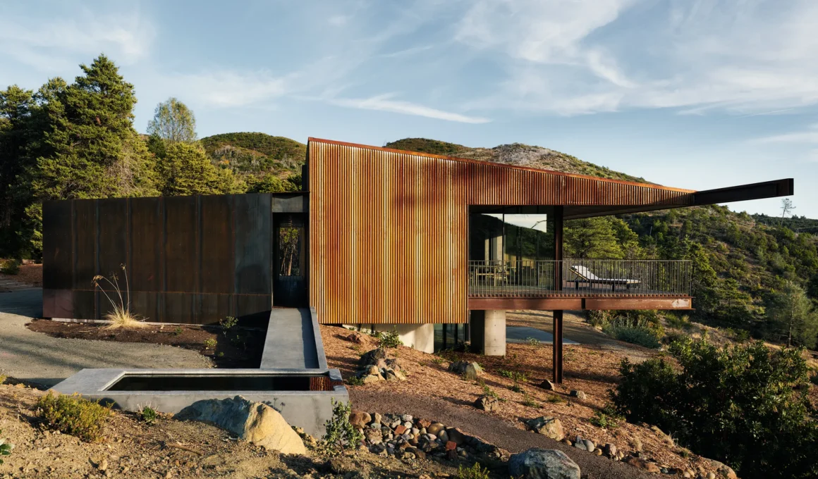A cantilevered Corten steel house with a concrete entry ramp and water basin in California.