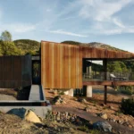 A cantilevered Corten steel house with a concrete entry ramp and water basin in California.