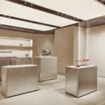 Automotive engine components displayed on minimalist silver plinths in a neutral gallery setting.