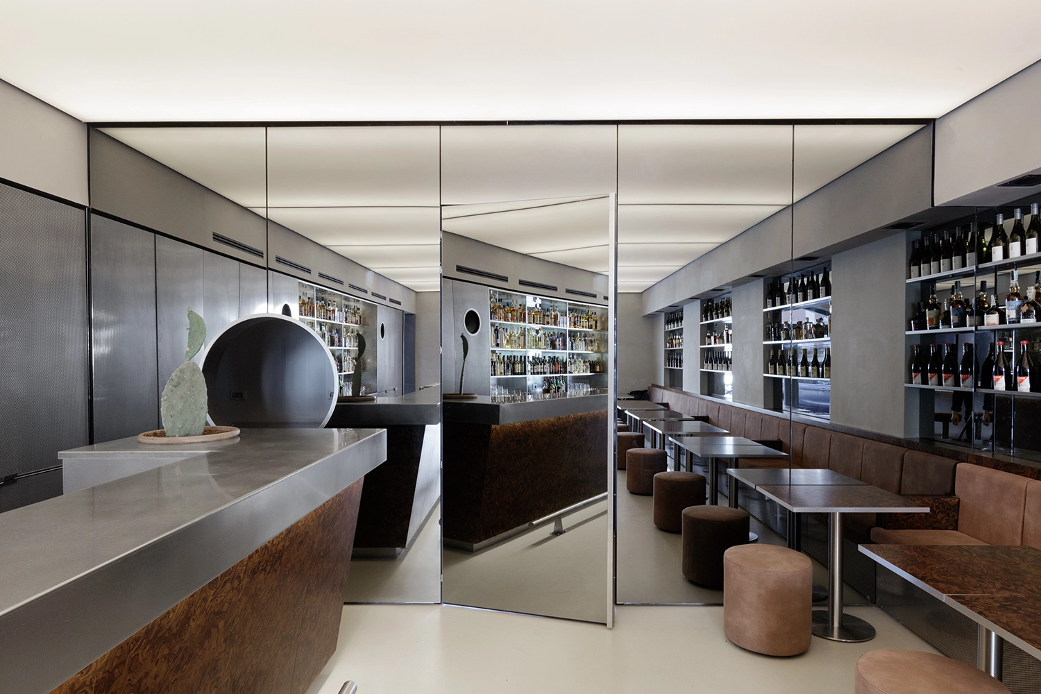 Mirrored wall at FEAT. cocktail bar reflecting the linear counter and providing an optical expansion of the narrow space.