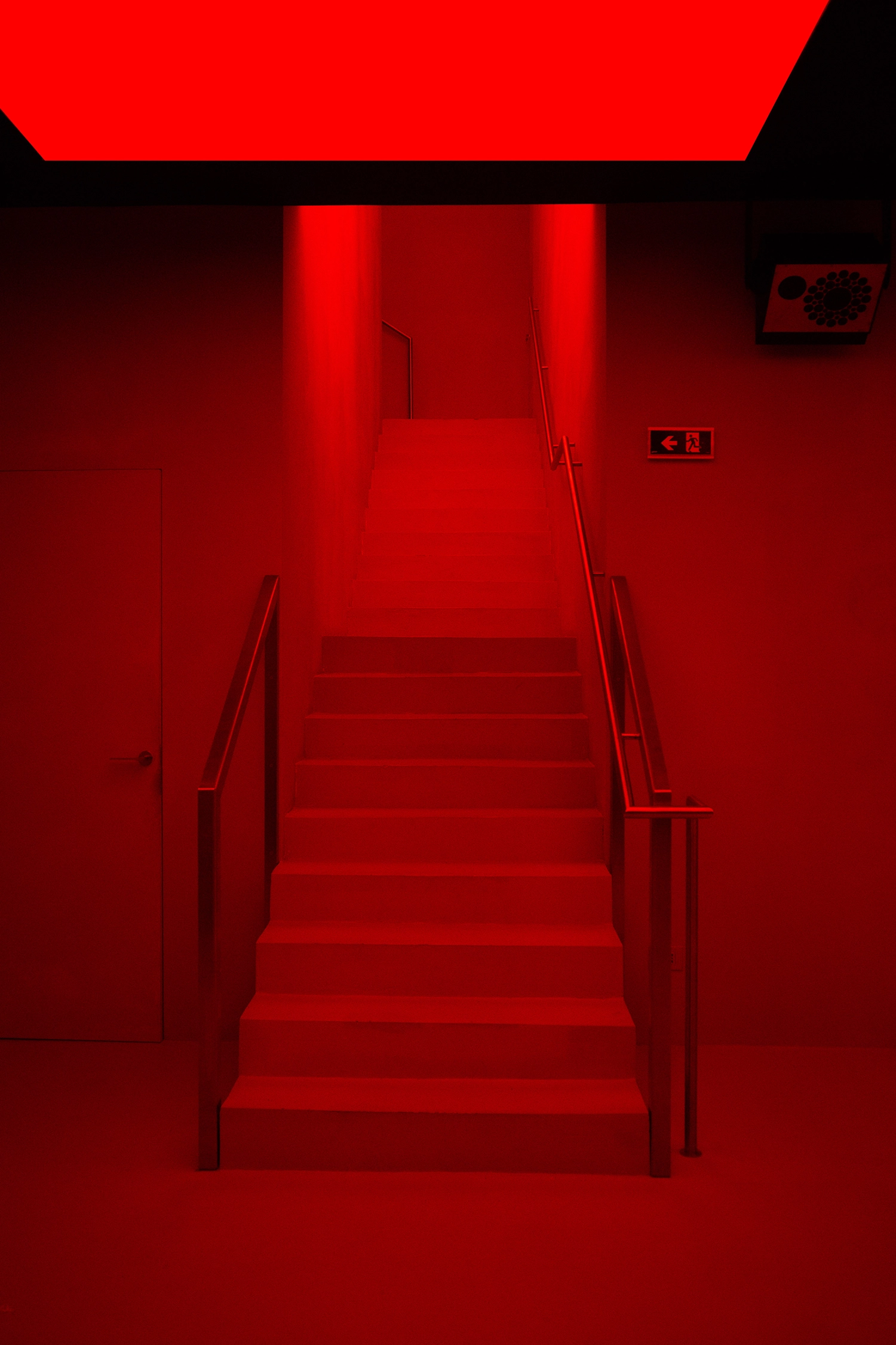 Symmetrical view of a staircase at FEAT. Milan completely saturated in red RGB light.