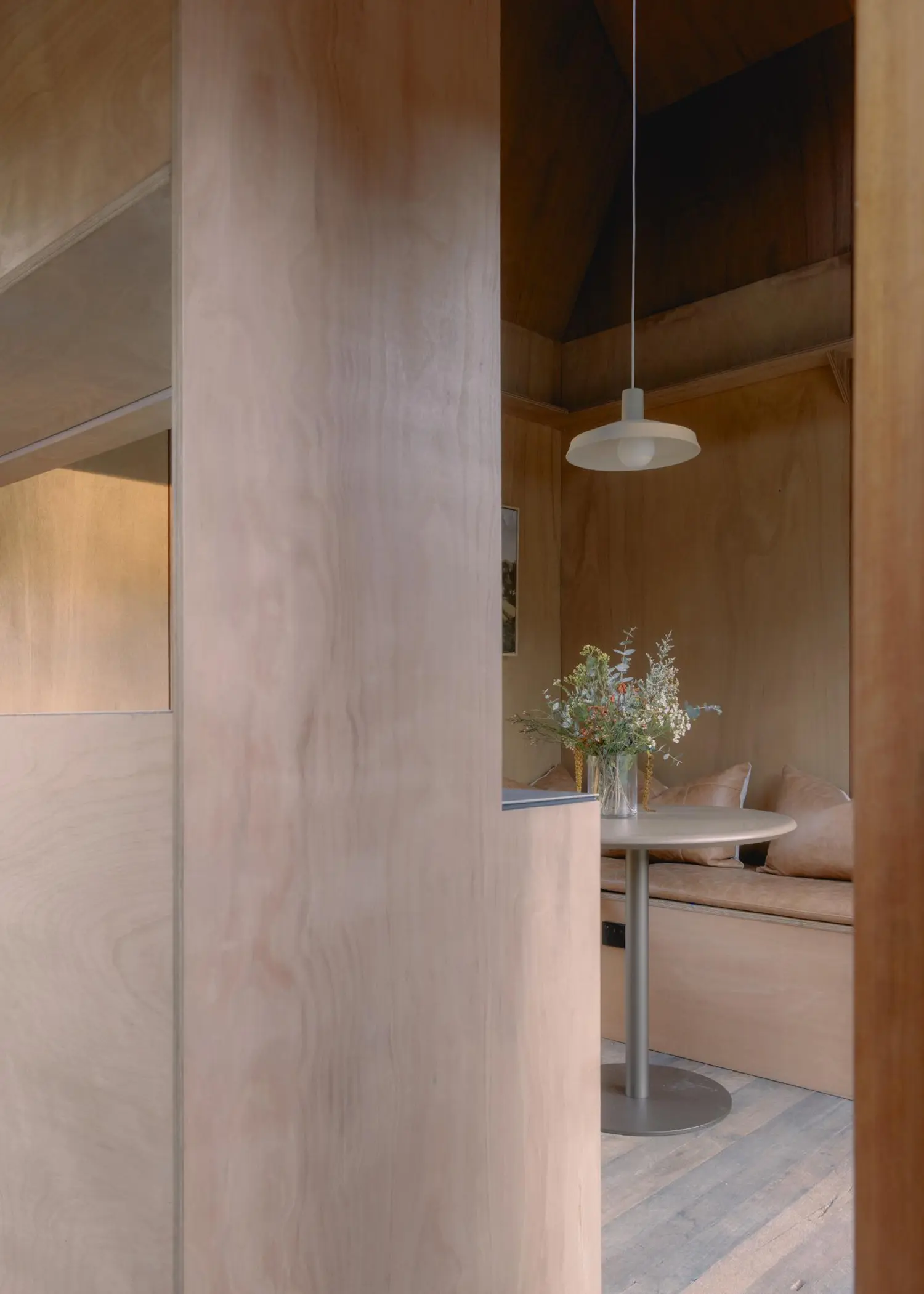 Interior detail of the Oculus dining area featuring a minimalist round table, leather cushions, and a pendant light.