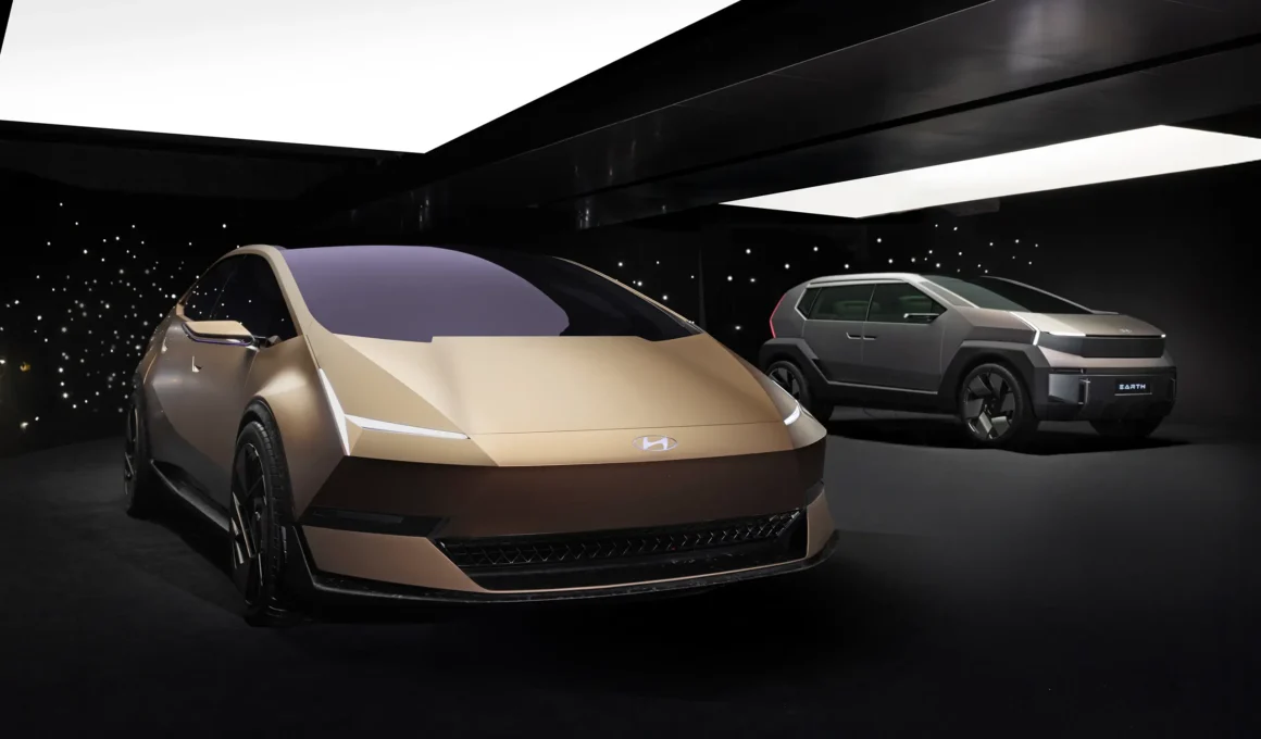 Two Hyundai IONIQ concept cars, the gold VENUS sedan and grey EARTH SUV, displayed in a dark studio with a starry background.