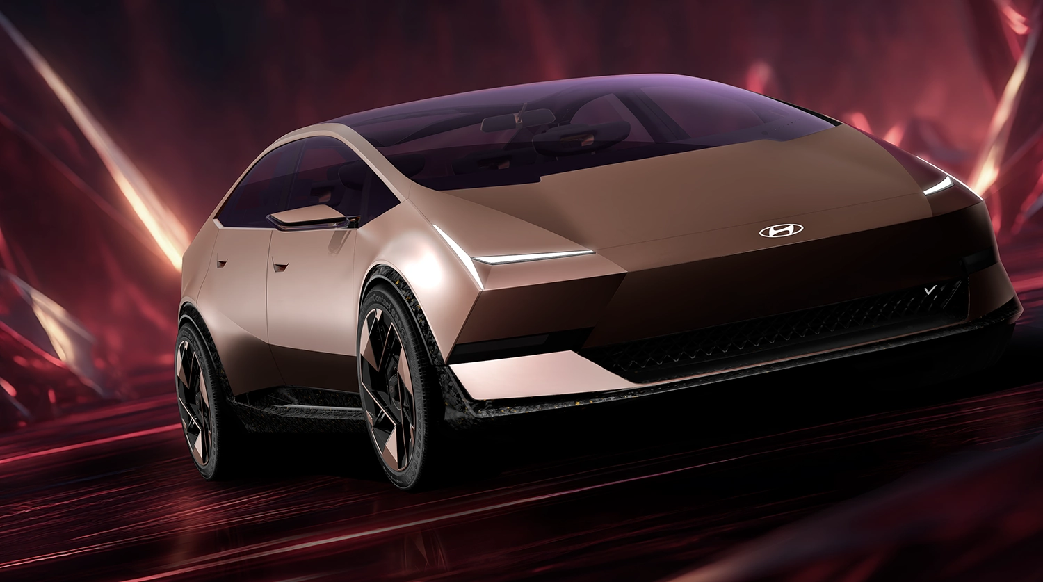 Side view of the Hyundai VENUS concept sedan in Radiant Gold with a sleek one-curve silhouette and aerodynamic wheels.